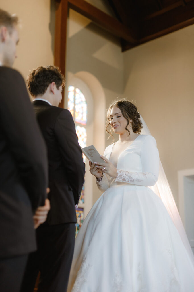 Bride reading vows during ceremony in white chapel in Pensacola florida