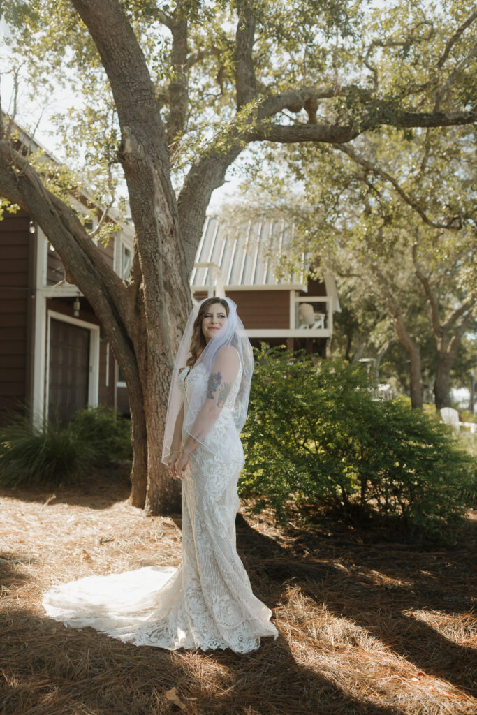 bride in dress next to a tree at outdoor wedding venue