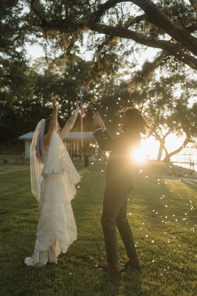 bride and groom sunset portraits with flower pedals next to water at wedding venue