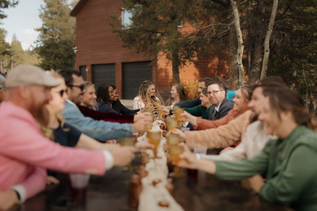 Head of the table moment with brides surrounded by family at outdoor dinner