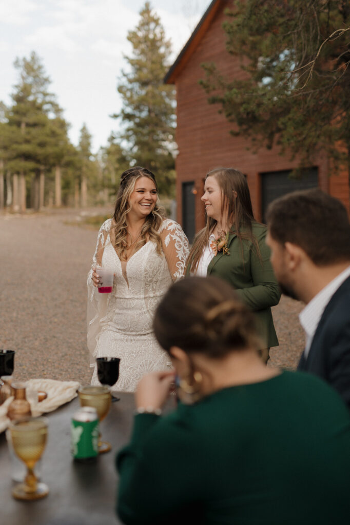 Head of the table moment with brides surrounded by family at outdoor dinner