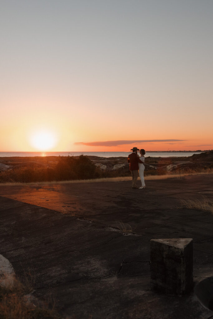Private first dance at sunset during Fort Pickens elopement, with bride holding her belly gently