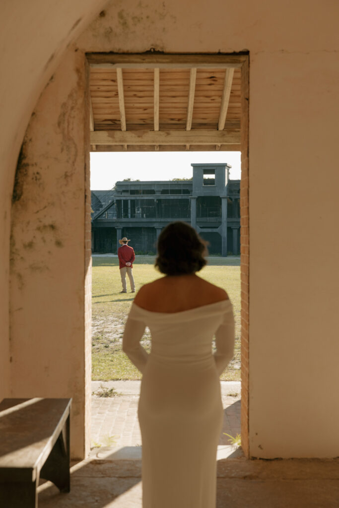 Bride standing quietly before her Fort Pickens elopement, holding flowers and taking a breath