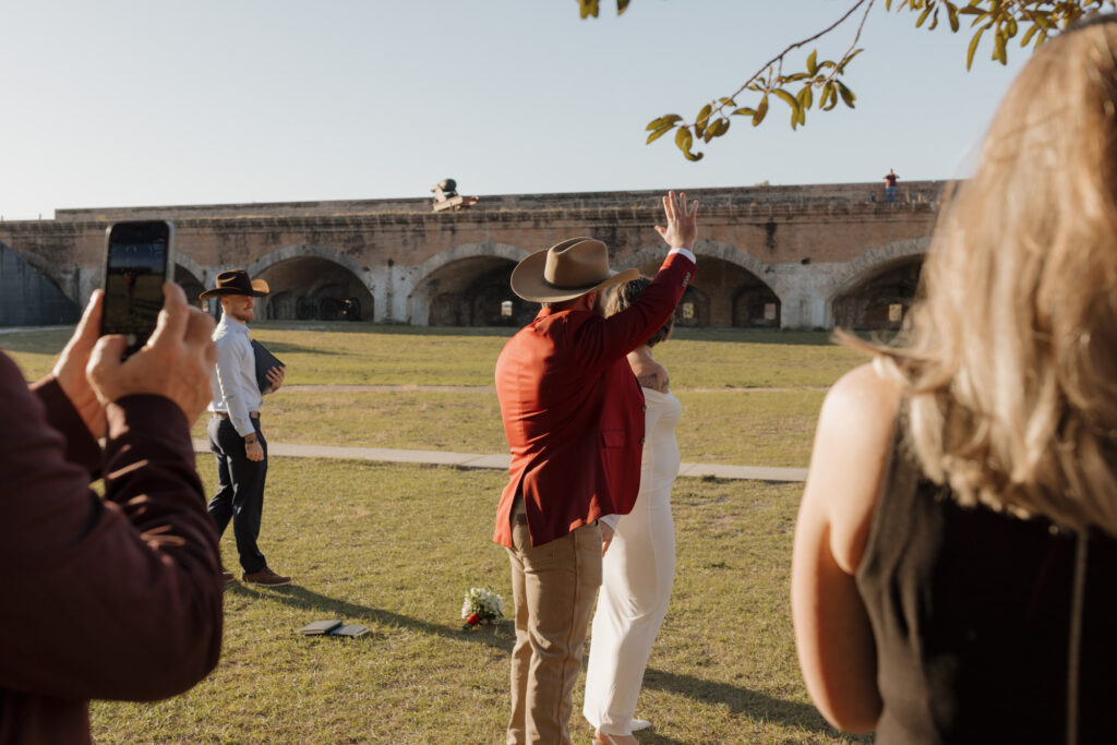 bride and groom waving at guests at fort pickens