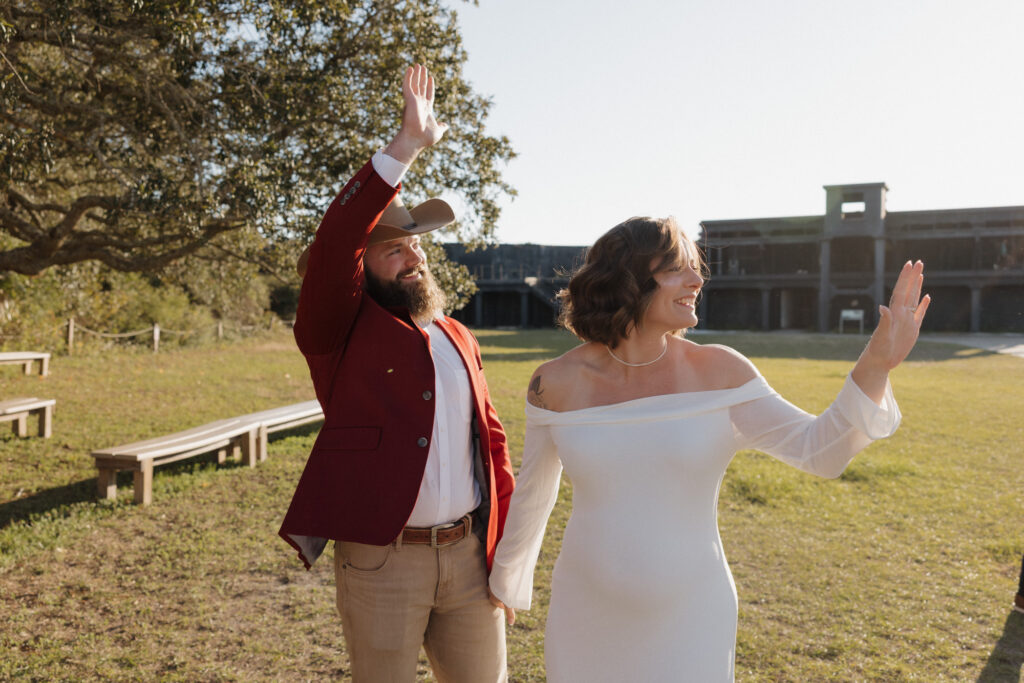 bride and groom waving at guests at fort pickens