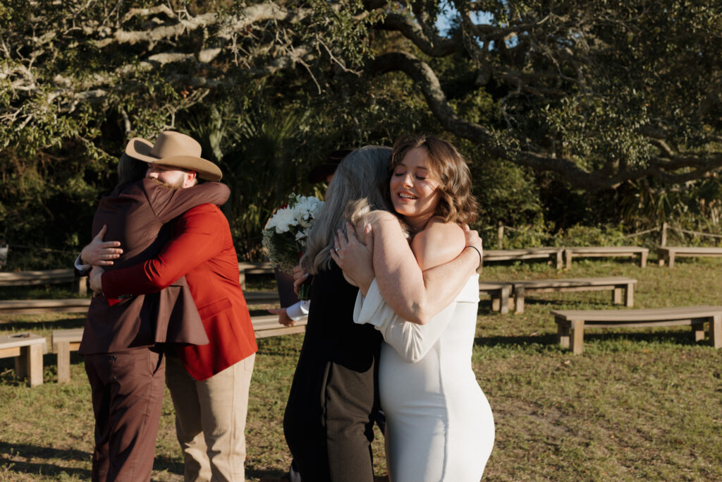 bride and groom hugging family after intimate elopement ceremony at fort pickens on Pensacola Beach