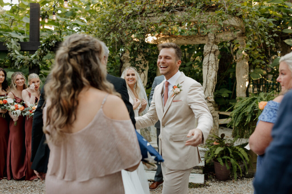 groom hugging bride's mom during garden ceremony at monet monet wedding venue