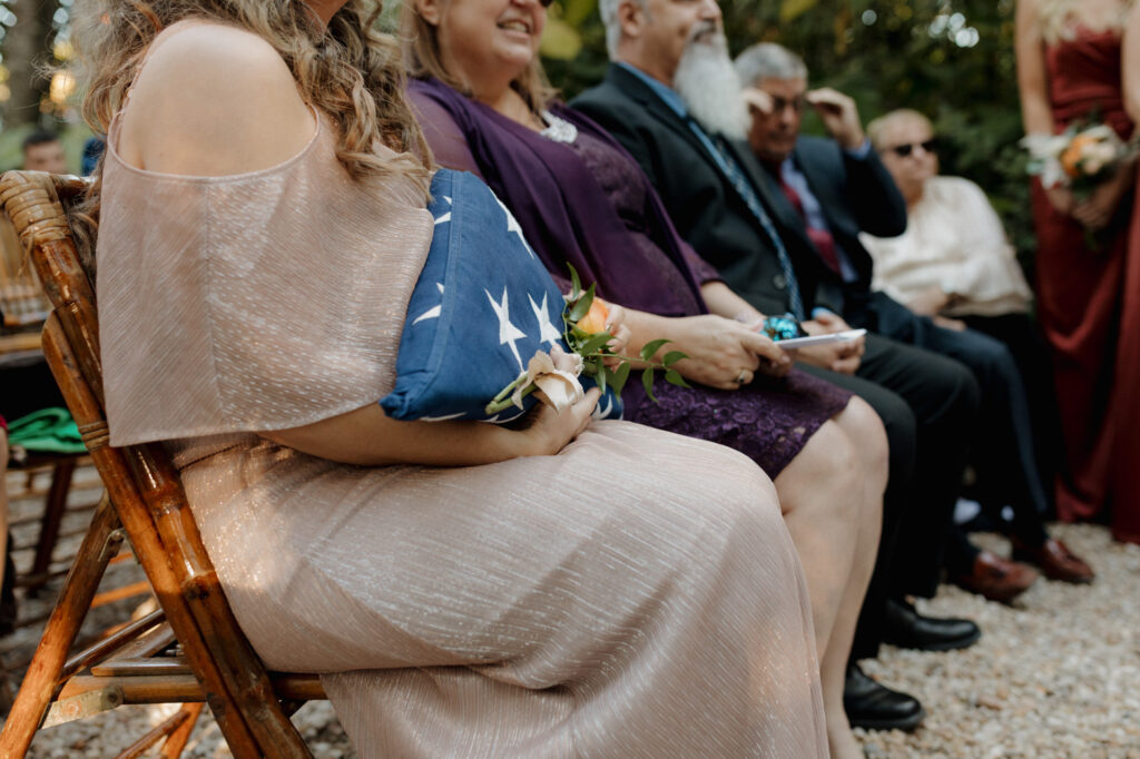 Bride’s mother holding folded flag in quiet moment of remembrance