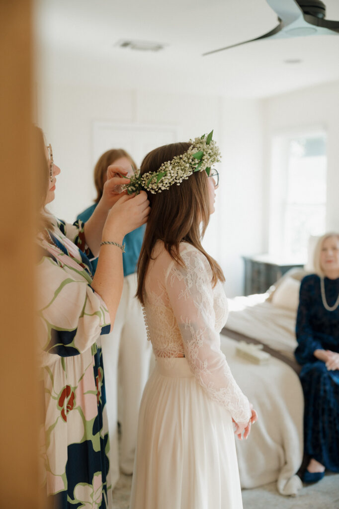 Bride slipping into her dress in a sun-filled room at a family beach house in Perdido Key