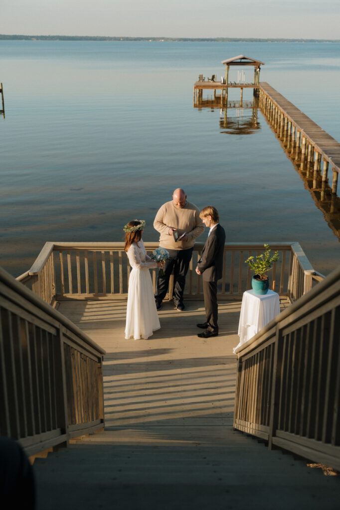 Bride and groom exchanging vows on a wooden dock during their intimate Perdido Key wedding ceremony