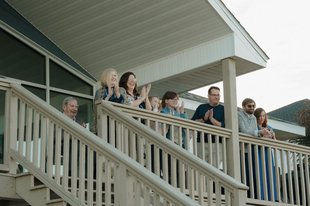 Guests celebrating with quiet joy as the couple kisses at the end of their dockside vows