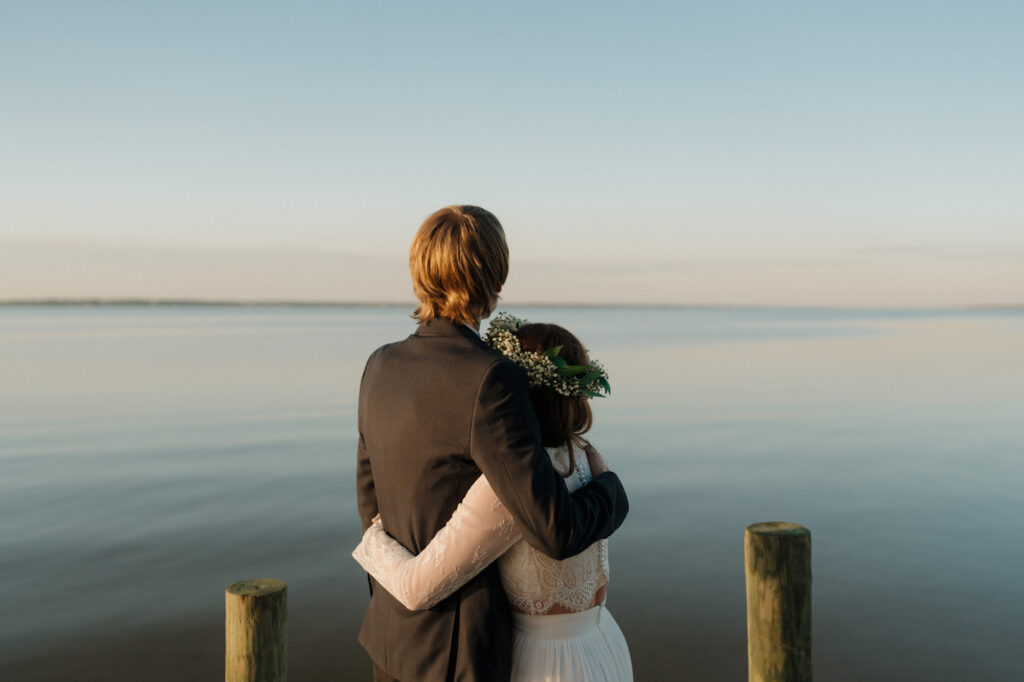 Relaxed, unposed couple portrait on a wooden dock with water in the background
