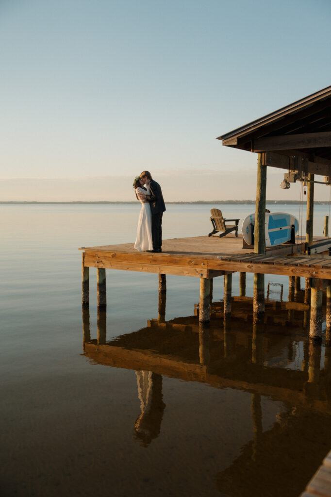 Relaxed, unposed couple portrait on a wooden dock with water in the background