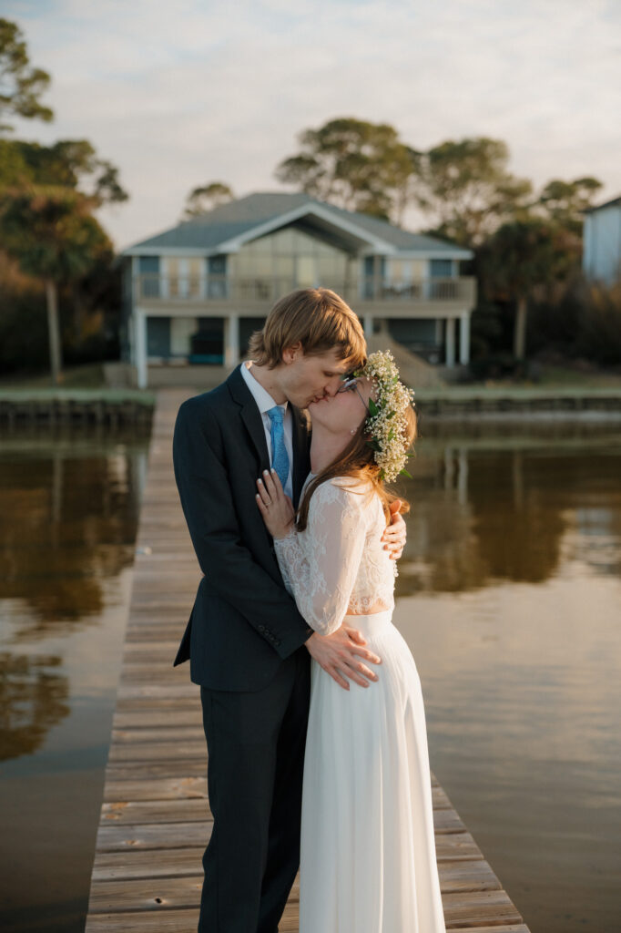 Relaxed, unposed couple portrait on a wooden dock with water in the background